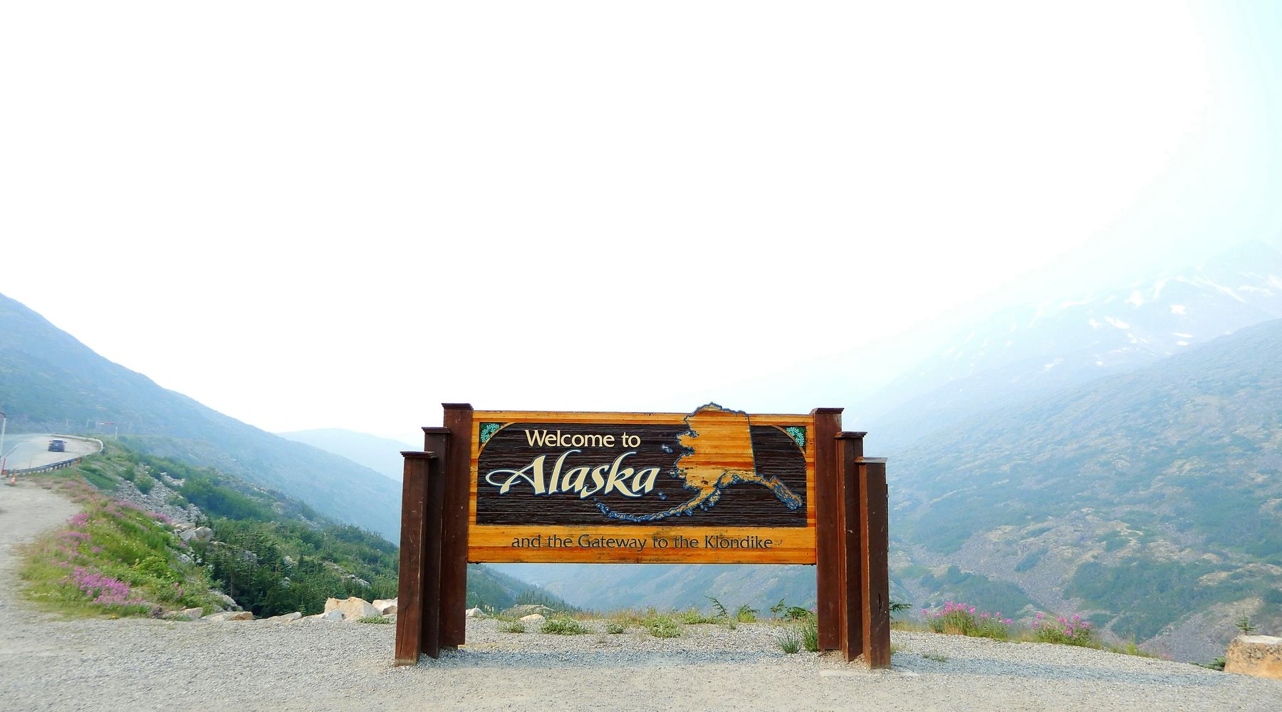 The Welcome to Alaska sign on the Klondike Highway above Skagway, with the valley falling away behind it