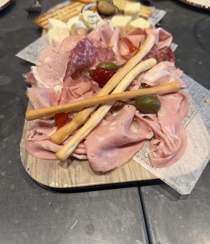 A wooden board of sliced cured meats, cheese cubes, breadsticks and pickled peppers at Giovanni's Kitchen on Harmony of the Seas.
