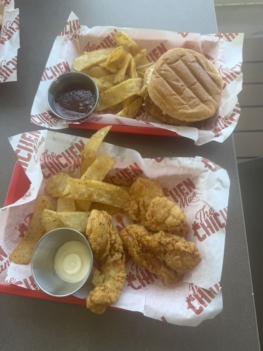 Two trays at The Chicken Man on MSC Seashore, one with a chicken sandwich and fries, the other with chicken tenders and fries