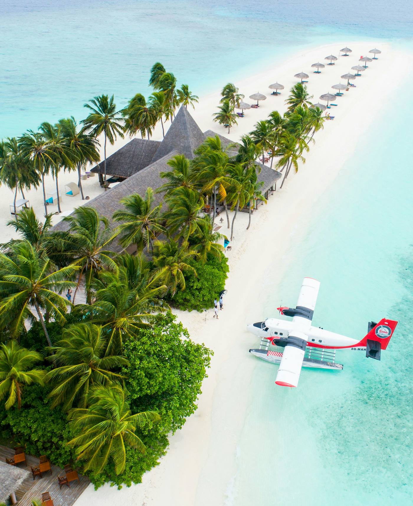 Aerial view of a luxury resort island with white sand beach and seaplane