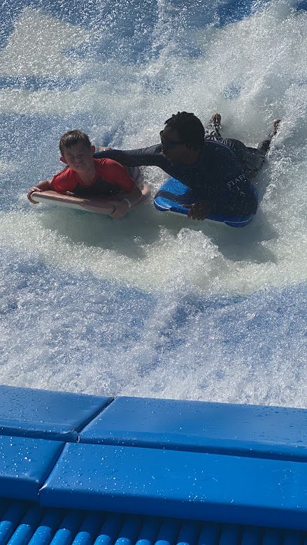 Jaxon riding the FlowRider with help from an instructor on a Royal Caribbean cruise.